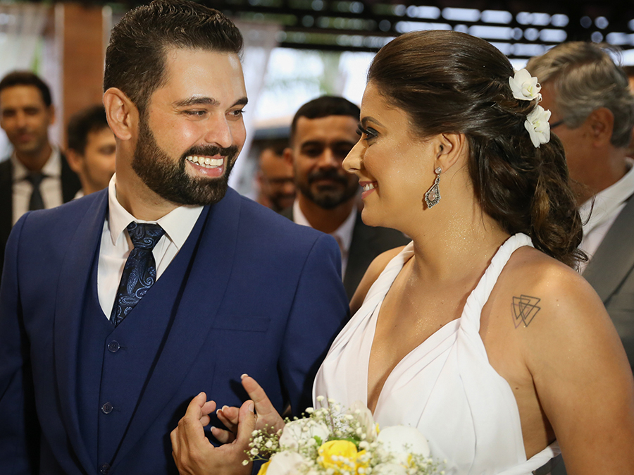 Noivo recebe noiva para cerimônia. Os dois se olham e sorriem uma para o outro. foto feita em meio corpo