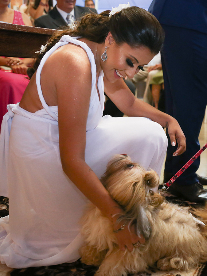 Noiva se agacha para receber aliança de sua cachorrinha, que recebe um carinho