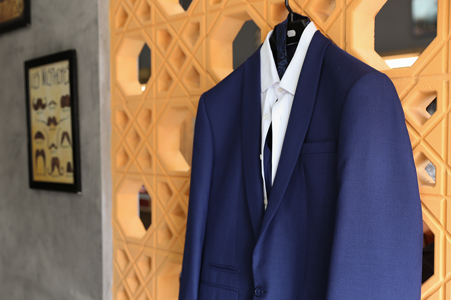 Detalhe do making of do noivo na barbershop, terno pendurado