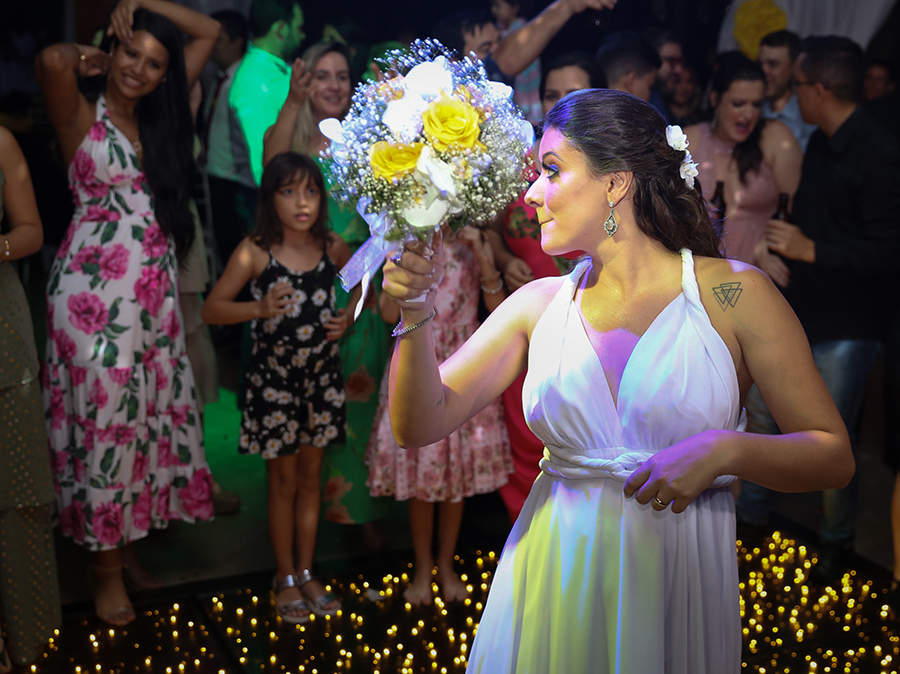 Tão esperada hora de jogar o buquê. Detalhe da noiva brincando com as convidadas amaçando jogar o buquê