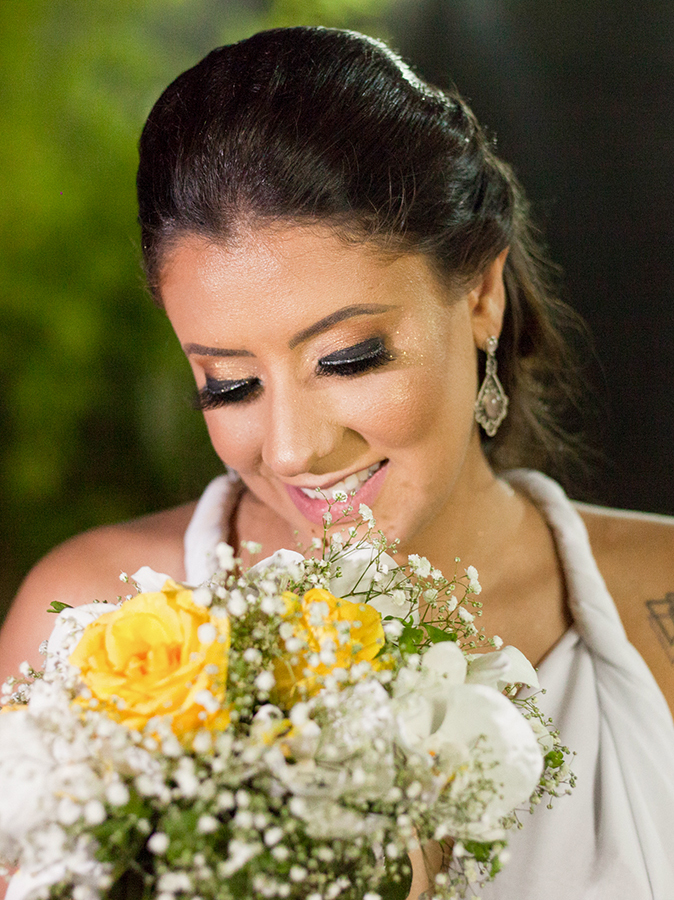 Retrato da noiva com buquê. Noiva sorri e olha para o buquê