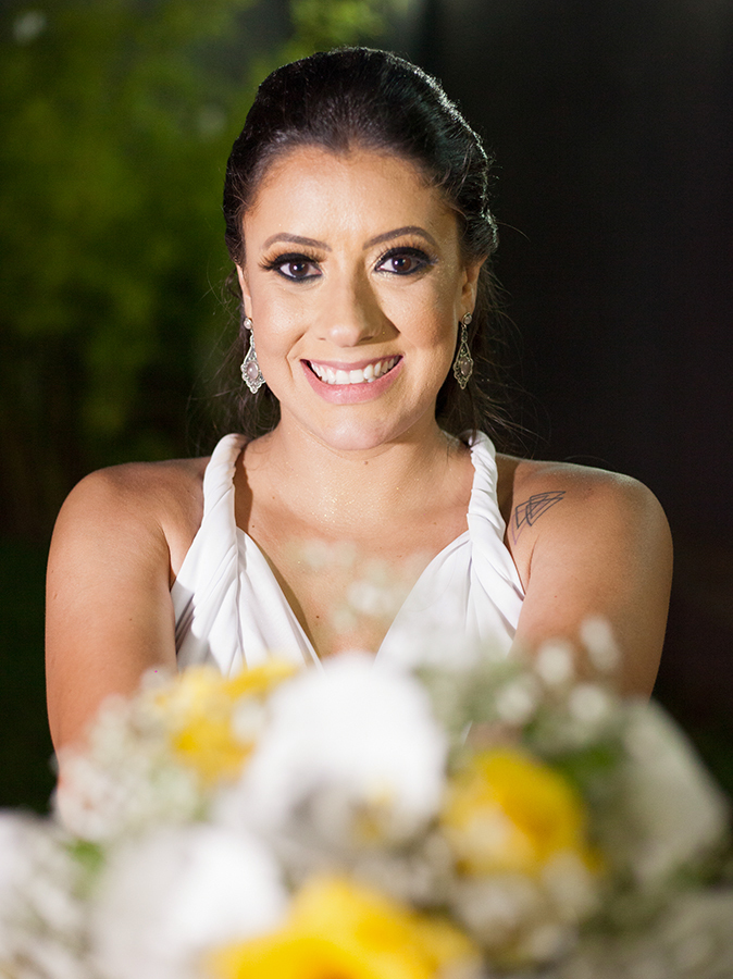 Retrato da noiva com buquê. Noiva leva buquê ao primeiro plano, que está desfocado