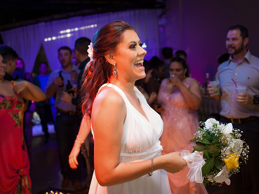 Tão esperada hora de jogar o buquê. Detalhe da noiva brincando com as convidadas amaçando jogar o buquê. Noiva de costas para convidadas sorrindo