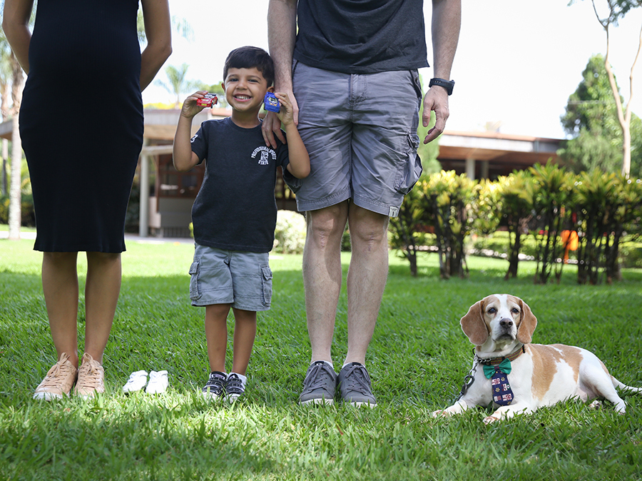 Toda família alinhada na grama. Mostrando pés da mamãe, sapatinho do Tomás, Heitor com sues carrinhos, pés do papai e cachorro no final