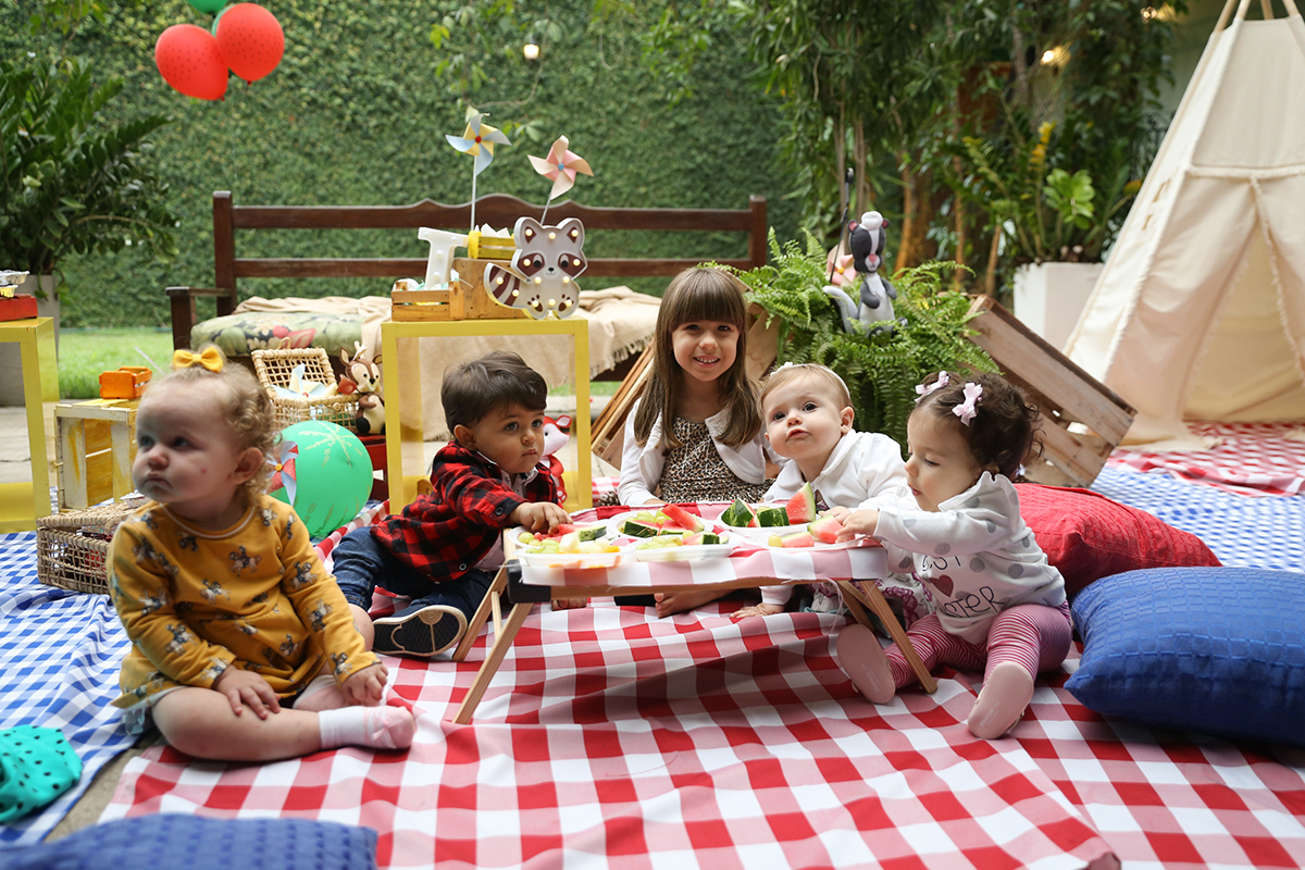 Crianças brincam e se divertem no picnic, comendo frutinhas