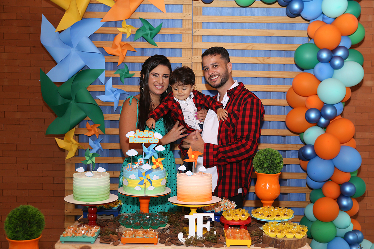 Paipai e Mamãe posam com aniversariante atrás da mesa do bolo antes do parabéns