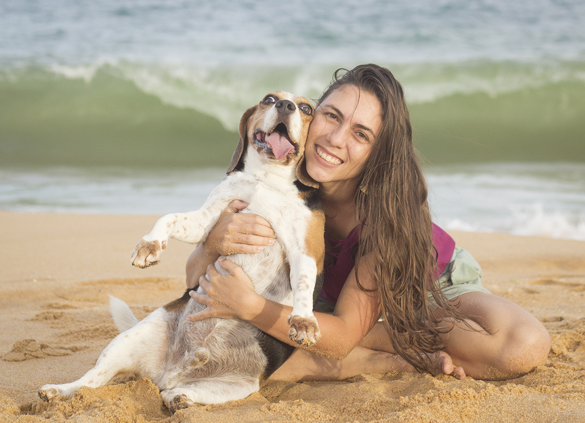 Marina posa com Billy, na areia da praia. Ele sentado com cara de alegria