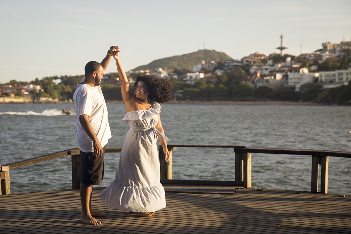 casal brinca de rodar, no deck com mar ao fundo