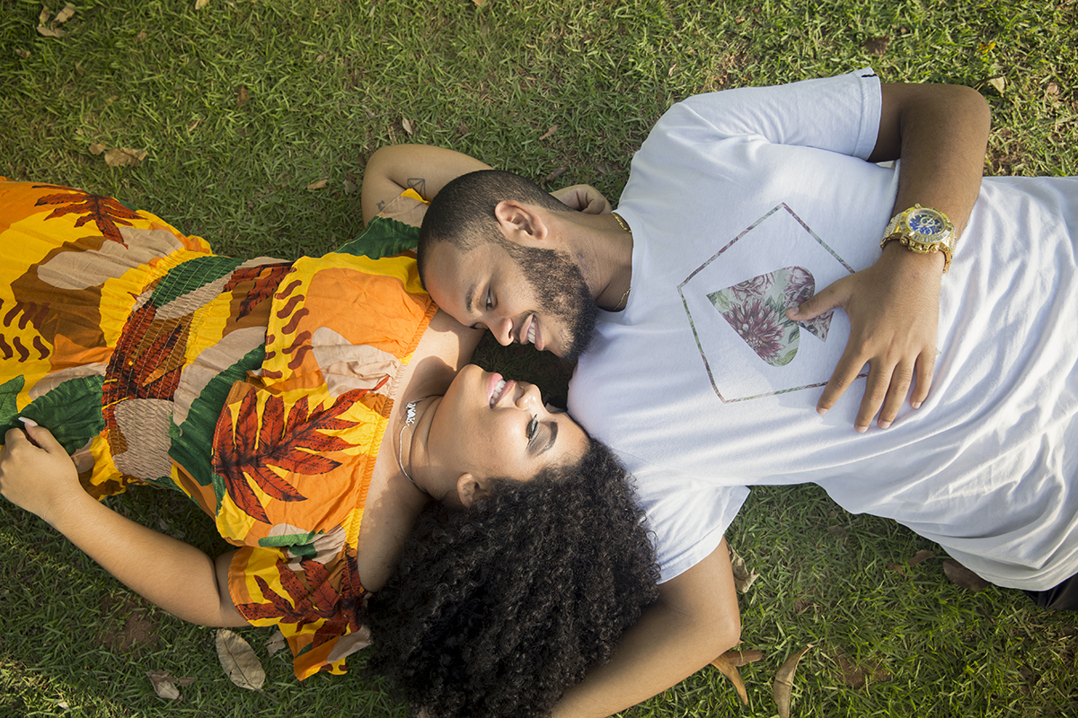 foto de cima, mostrando casal deitado na grama, olhando um para o outro