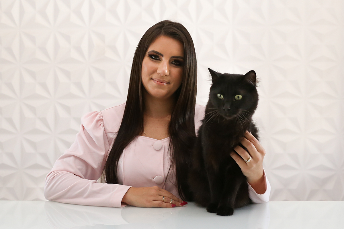 Veterinária posa para foto junto com seu gato no consultório