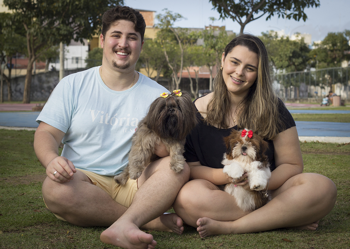 Amora e Cléo posam para foto no colo de seus papais humanos