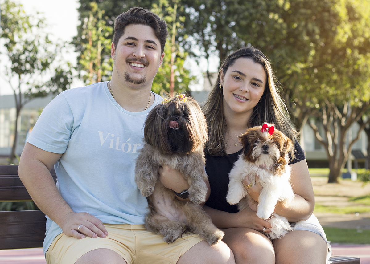 Amora e Cléo posam para foto no colo de seus papais humanos