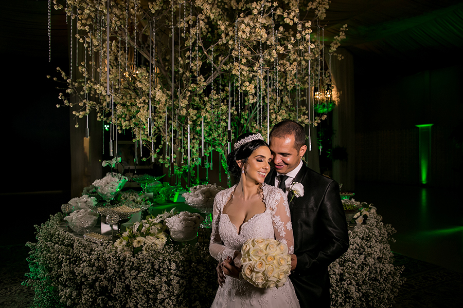 Casal pousando em frente uma das mesas de doces 