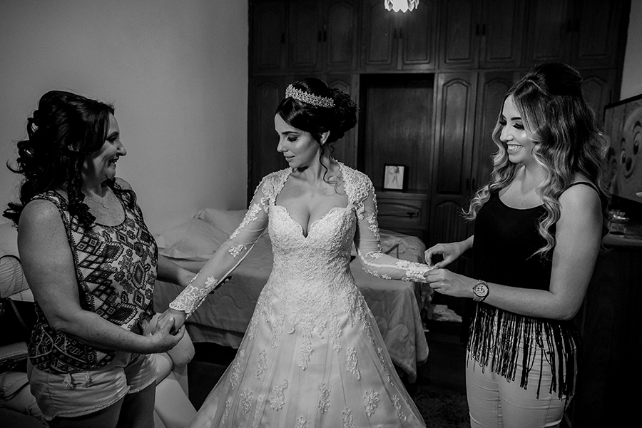 Mãe e a irmã ajudando a noiva se vestir
