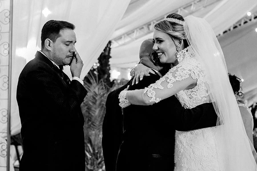 Noivo emocionado e noiva abraçando o sogro 