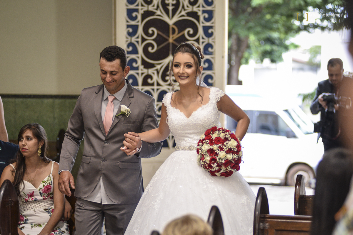 Entrada da noiva Letícia com o pai no seu casamento na Igreja Santa Terezinha em Patos de Minas-MG