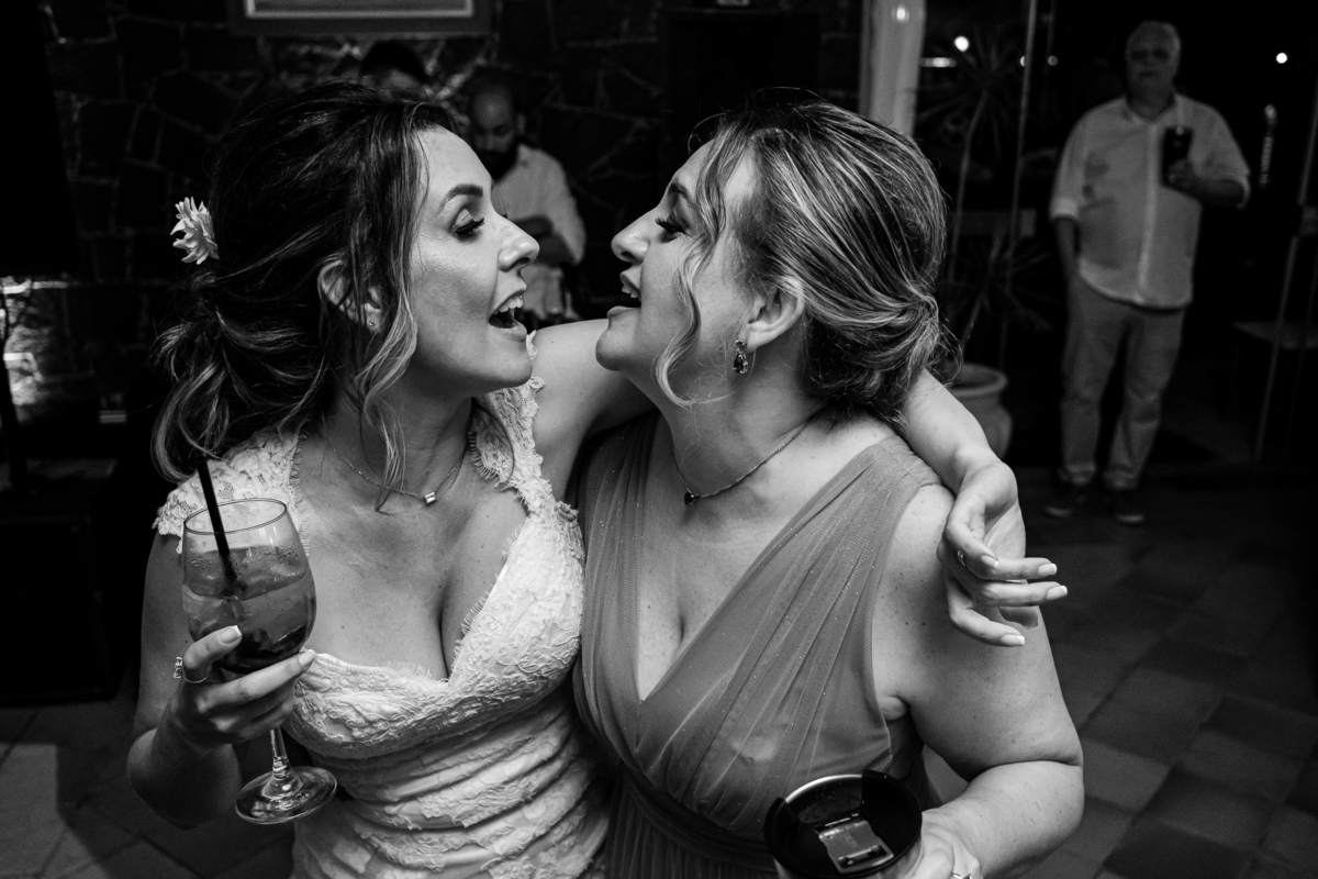 foto em preto e branco, noiva dançando animada com sua melhor amiga em seu casamento