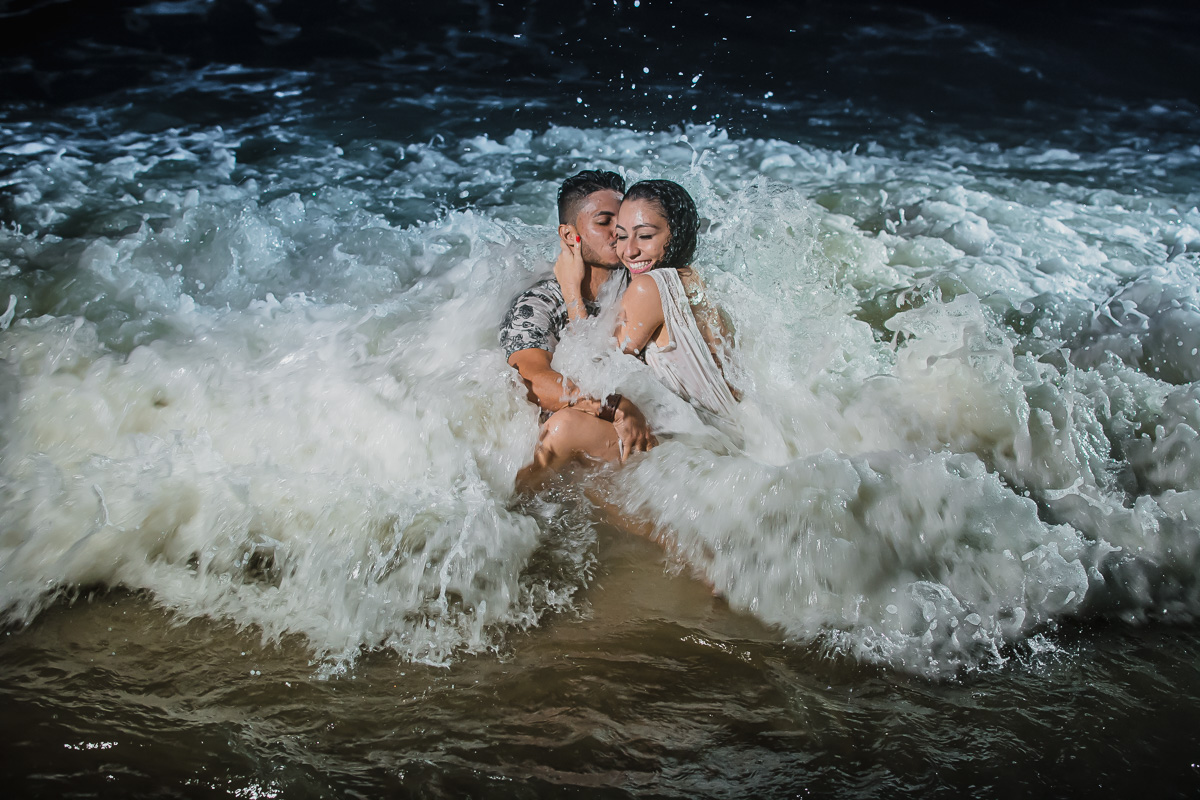 Fotos de casamento na praia com beijo dentro da agua em um dia incrível e divertido