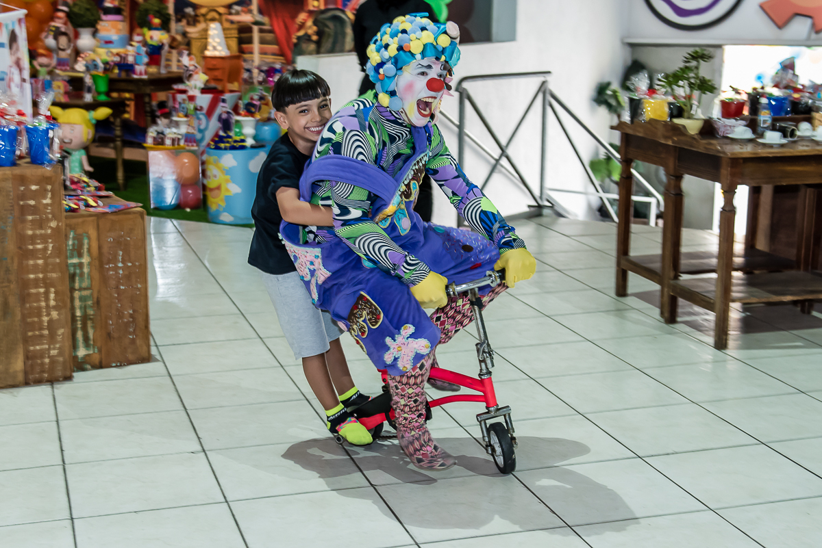 o palhaço da garupa na bicicleta pelo salão da festa