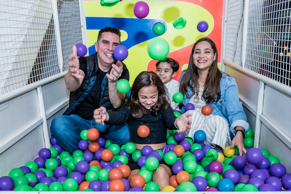 a família estão felizes brincando na piscina de bolinhas