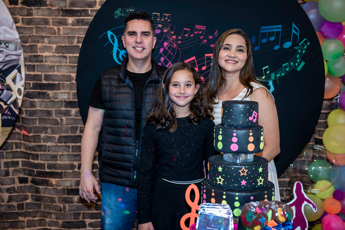 foto da aniversariante com os pais na mesa do bolo