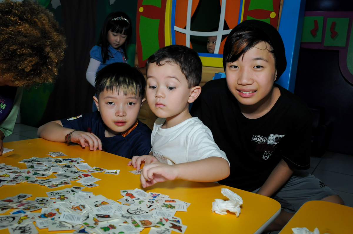 escolhendo figurinha para a tatuagem na FestaInfantil, fotografia infantil aniversário de Rafael 3 anos tema da festa Dinossauros no Buffet Mago Ra Tim Boom, Saúde, SP
