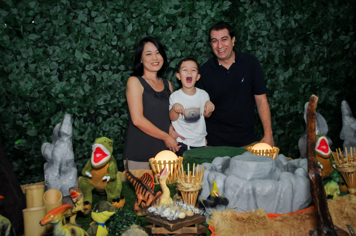Foto da família na mesa decorada no FestaInfantil, fotografia infantil aniversário de Rafael 3 anos tema da festa Dinossauros no Buffet Mago Ra Tim Boom, Saúde, SP