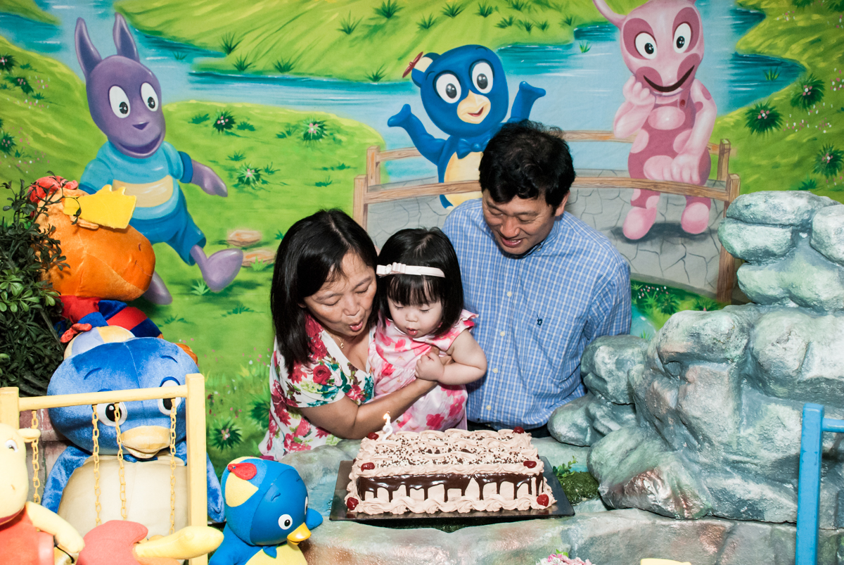 soprando a vela do bolo no fotografia da família na mesa temática no Buffet Viva Vida, Butantã, São Paulo, aniversário de Julia Yumi, tema da festa Backardigans