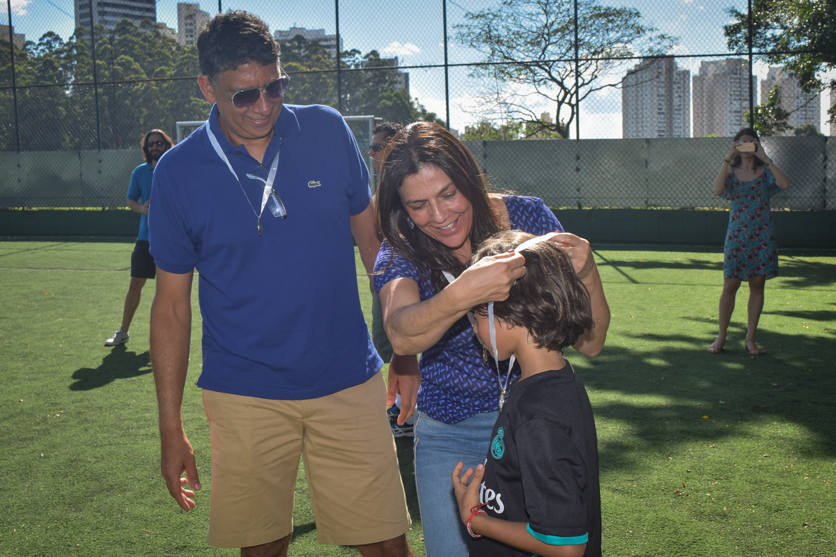 a mãe coloca a medalha no aniversariante no buffet High Soccer aniversario de João Pedro 8 anos, tema da festa Real Madrid