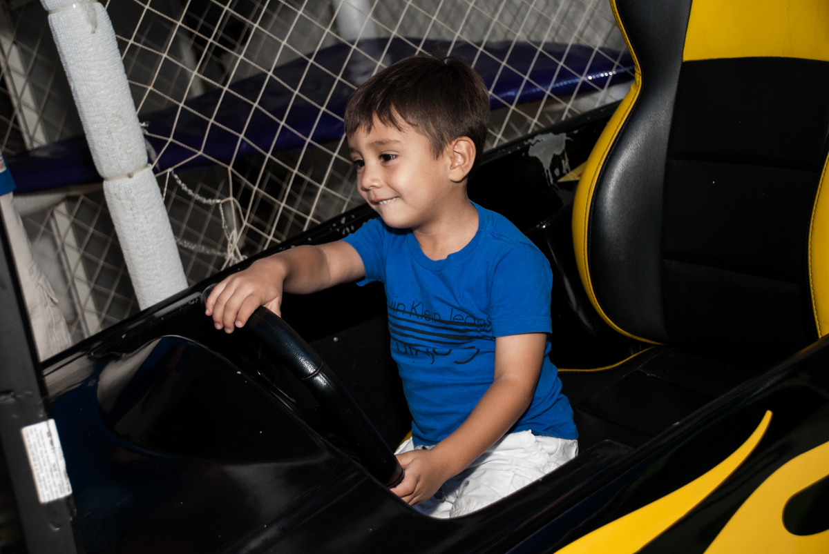 O amigo brinca no simulador de corrida no Buffet Fábrica da Alegria Morumbi, São Paulo, aniversário de João Pedro 4 anos tema da festa Batman
