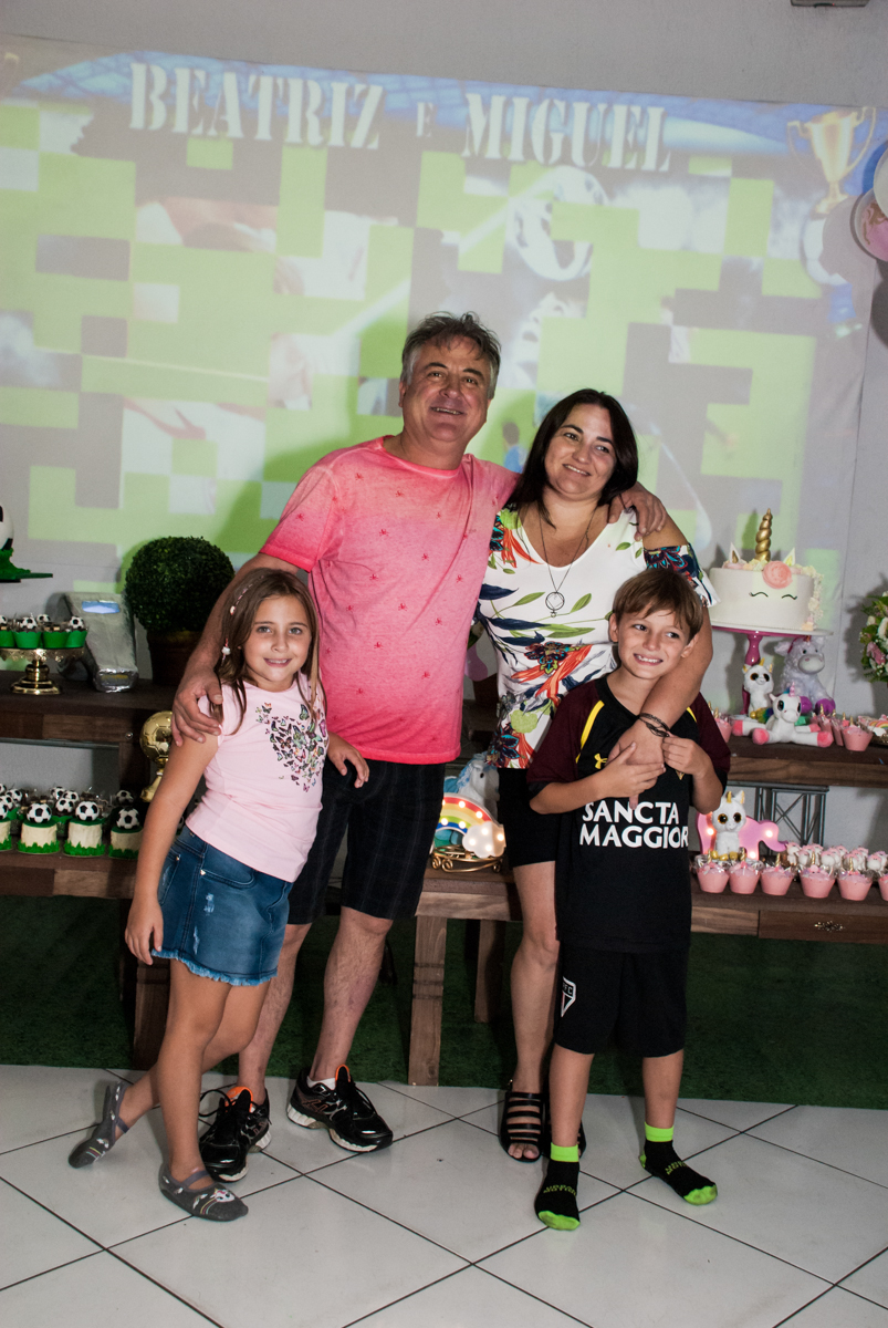 A família sendo fotografada no Buffet Fábrica da Alegria, Morumbi, São Paulo, aniversário de Beatriz e Miguel 8 anos, tema da festa Unicórnio e Futebol
