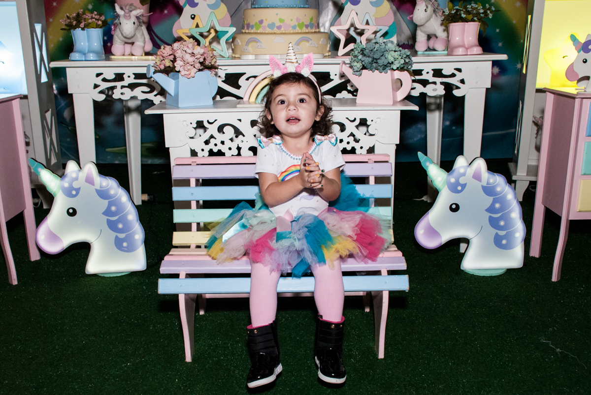 posando para a foto em frente a mesa temática unicornio