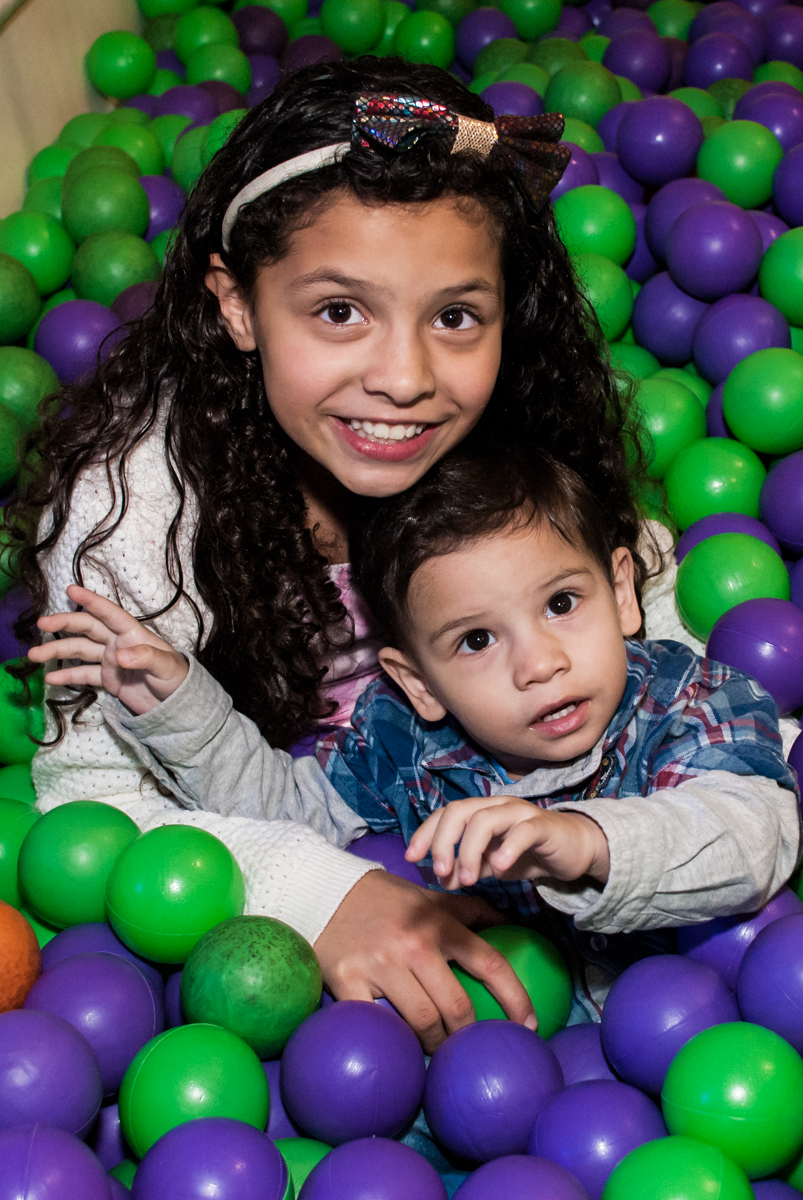 os irmãos brincam na piscina de bolinhas