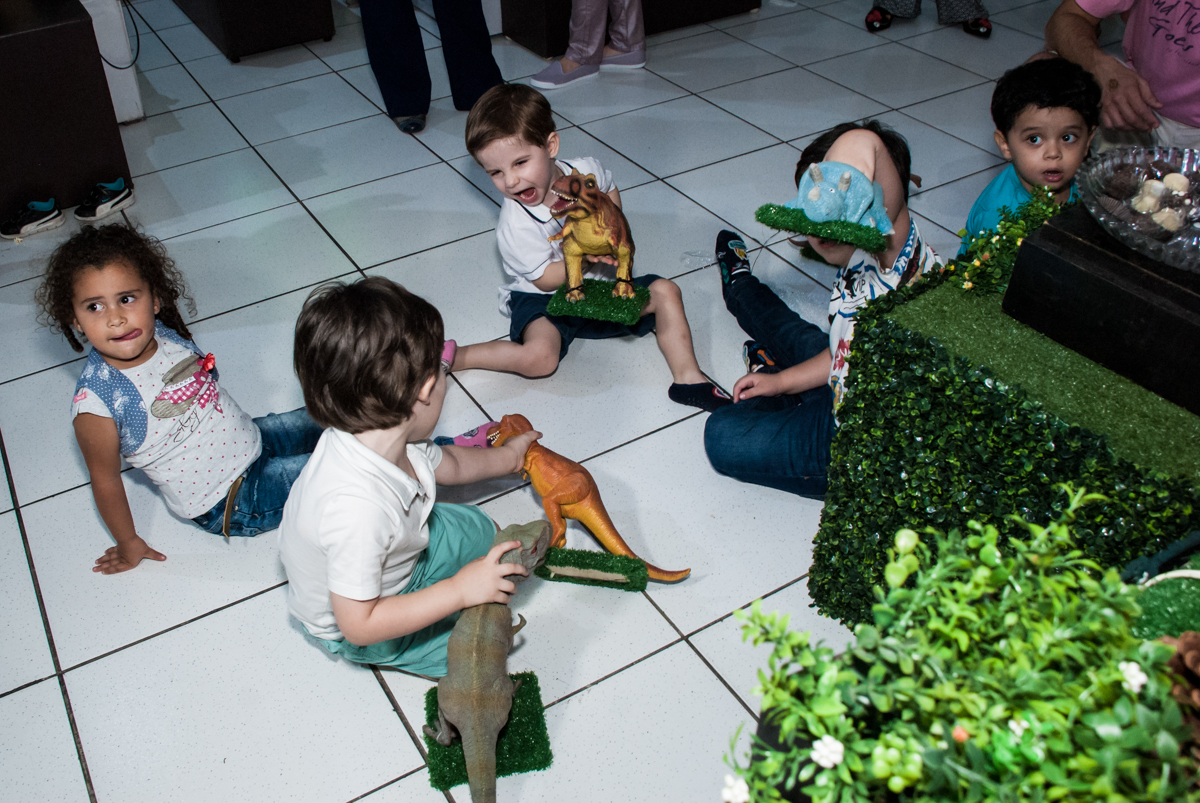 As crianças brincam com os dinossauros da mesa