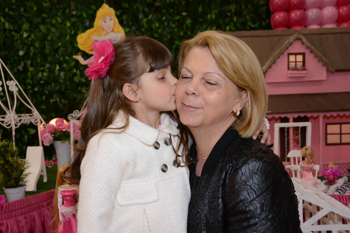 Fotografia da aniversariante beijando a vó em frente a mesa decorada Buffet Comics São Paulo SP