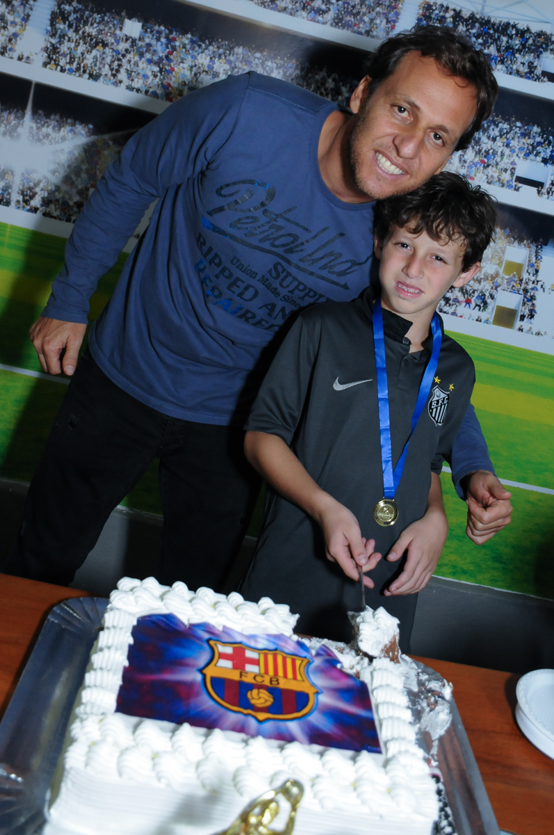 Fotografia do aniversariante com o pai na mesa do bolo no Buffet High Soccer