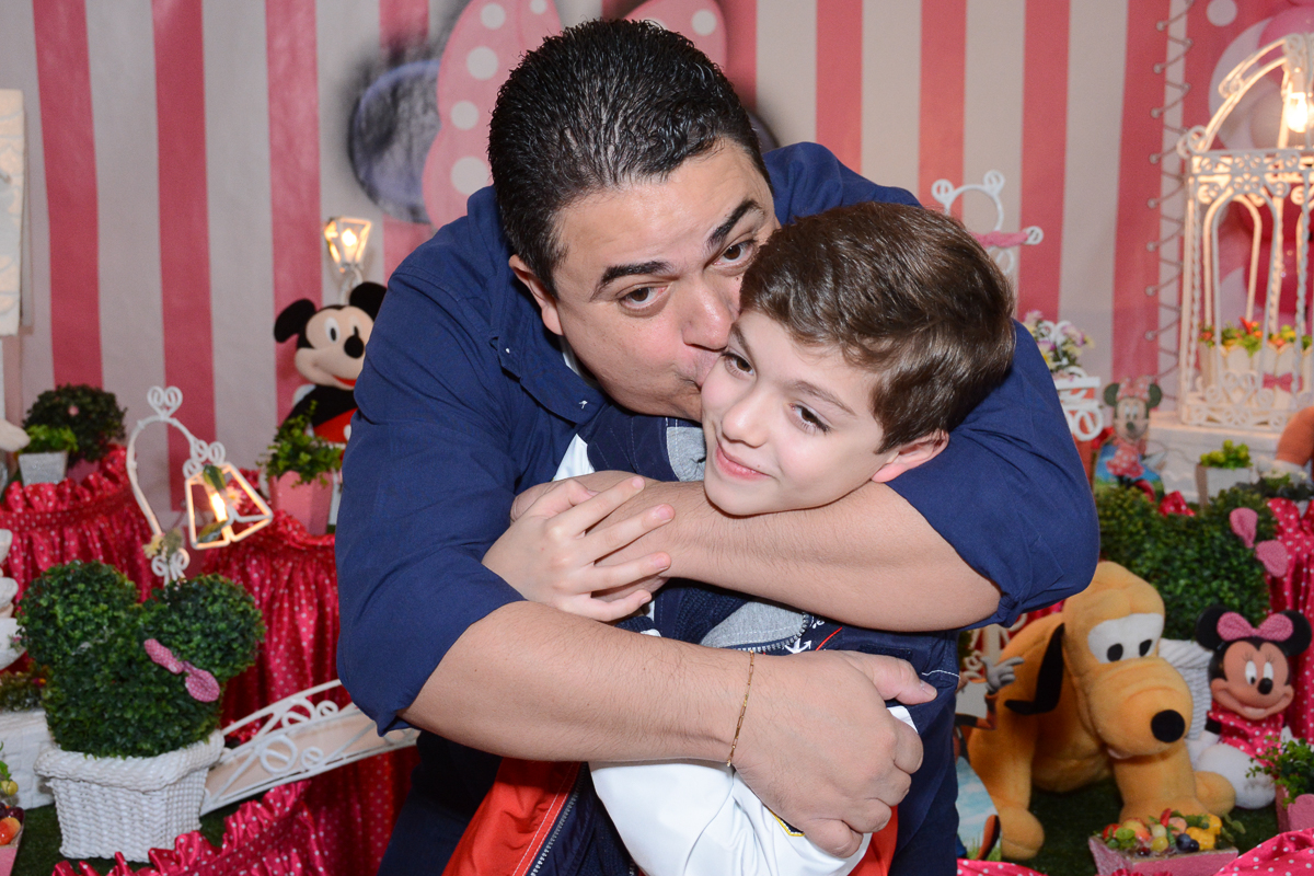 Papai beijando o irmãozinho de Lorena  em frente a mesa decorada  no Buffet Planeta Kids, São Paulo - SP