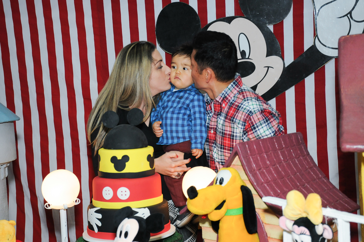 caio sendo beijado pelos pais na mesa do parabéns no fachada do buffet magic joy, saude