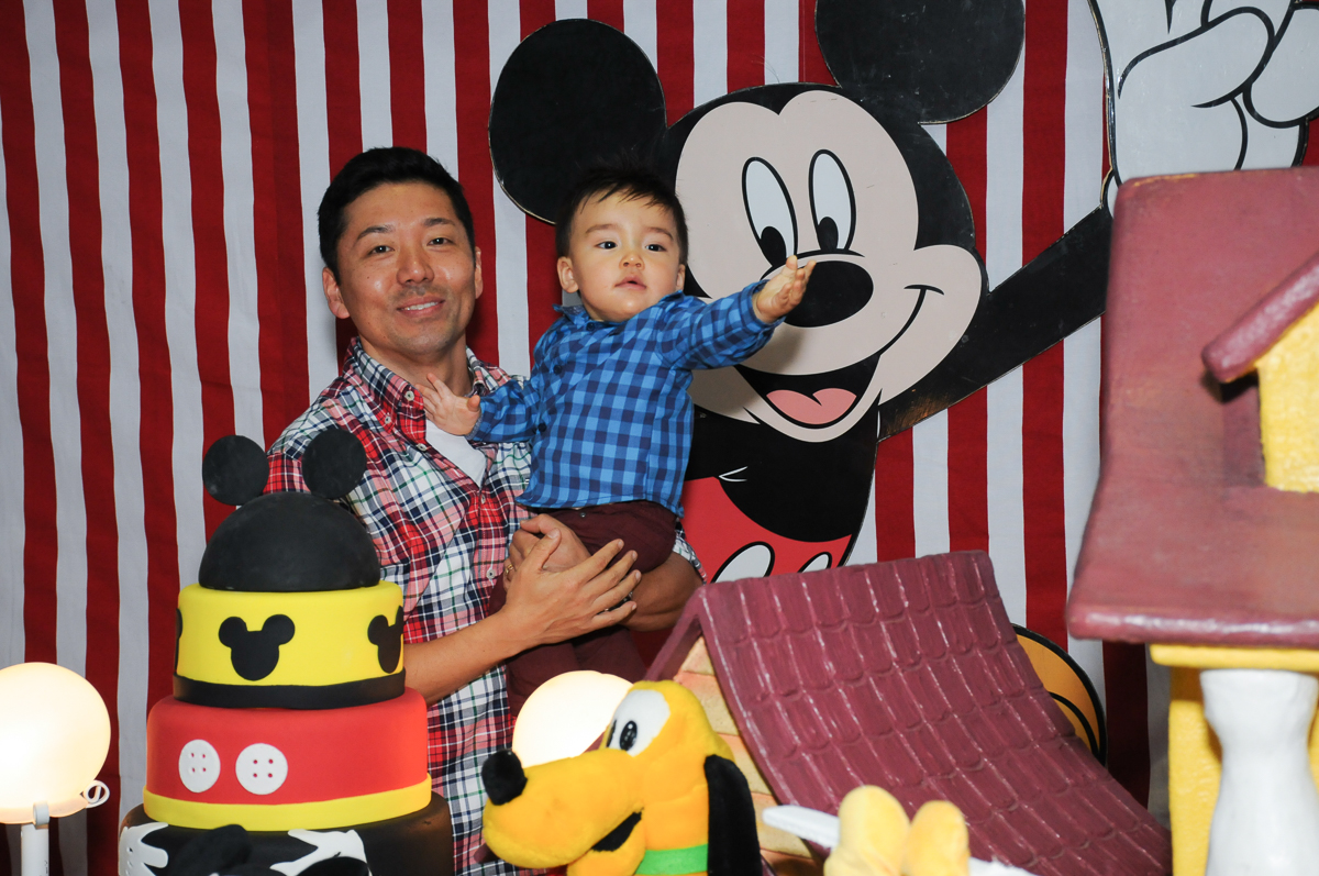 caio no colo do papai na mesa decorada do mickey no fachada do buffet magic joy, saude