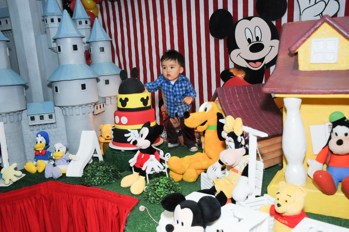 caio em pé na mesa decorada com os personagens do mickey no fachada do buffet magic joy, saude