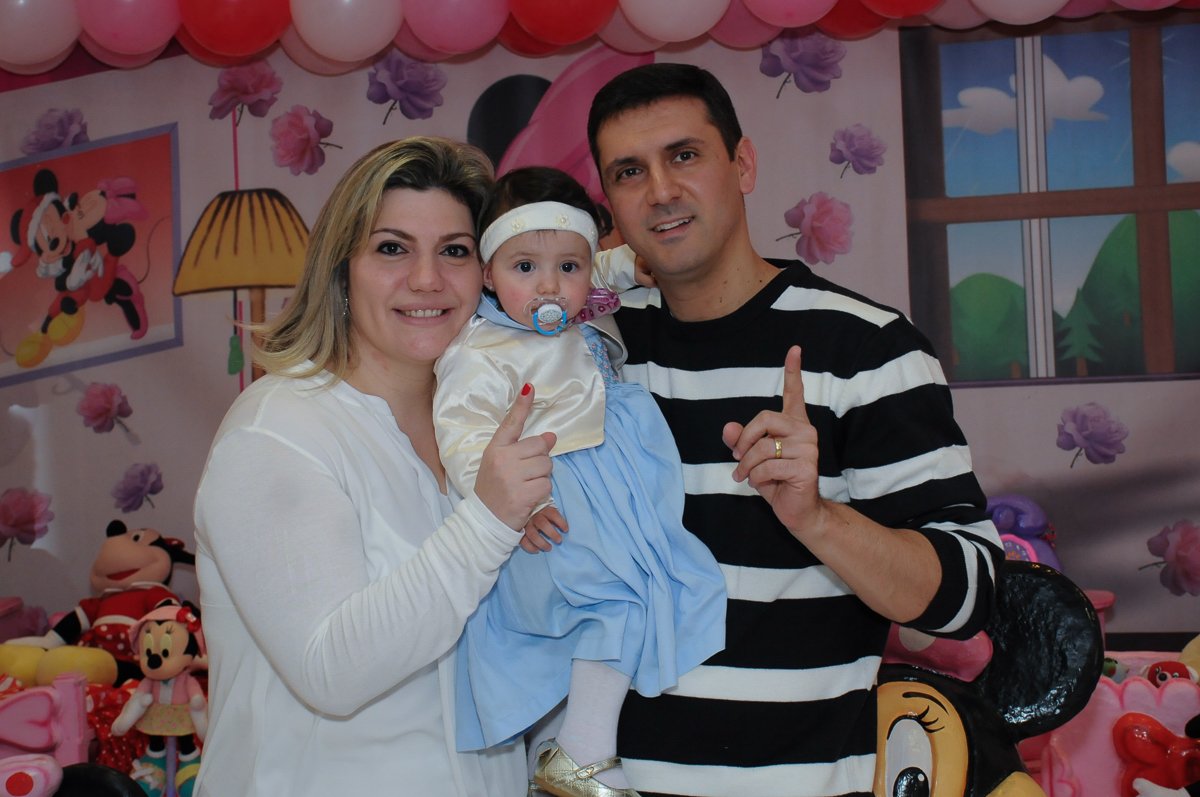 papai e mamãe com ana clara em frente a mesa decorada da minie no Buffet Lé com Cré