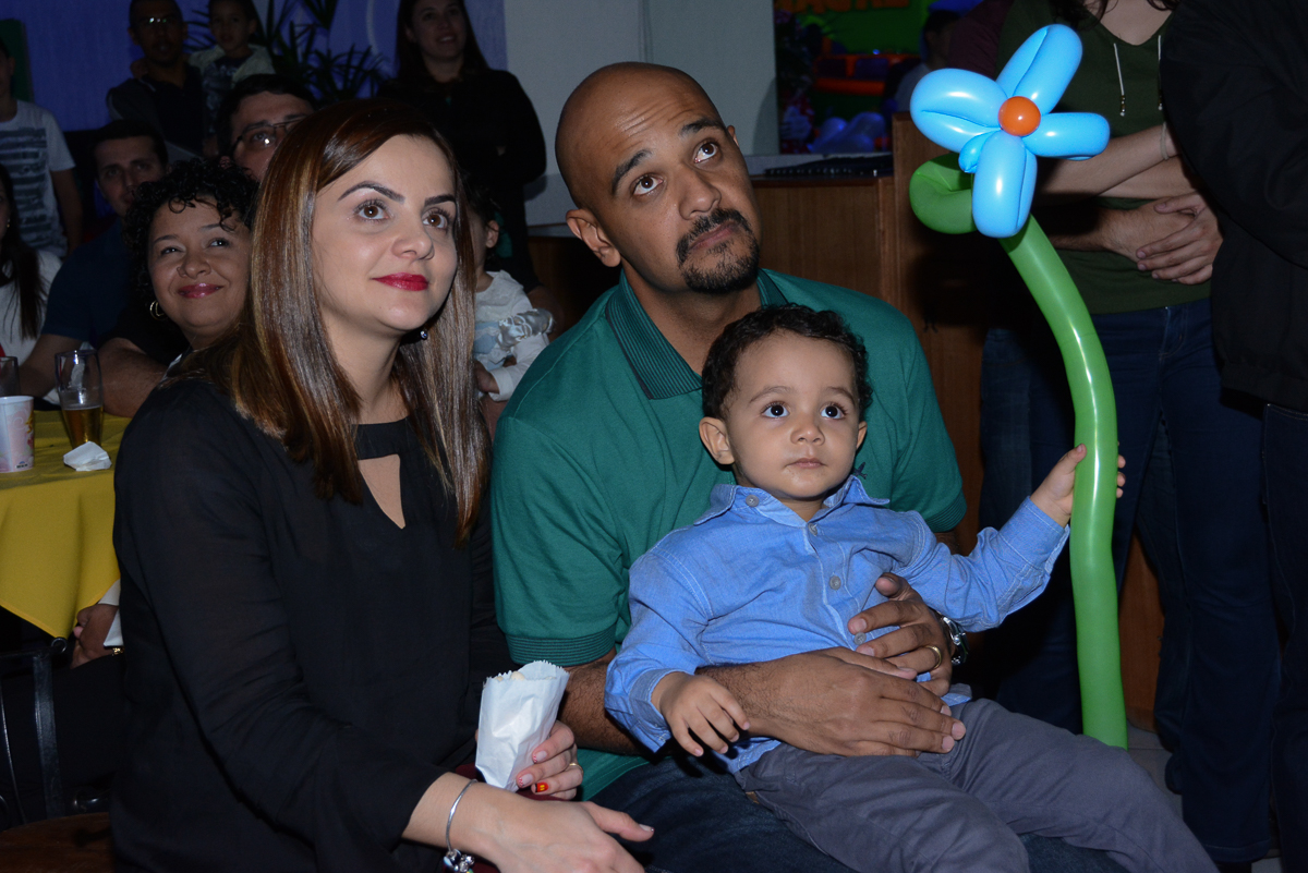 Matheus e os pais assistindo a retrospectiva no Buffet Fábrica da Alegria, Morumbi