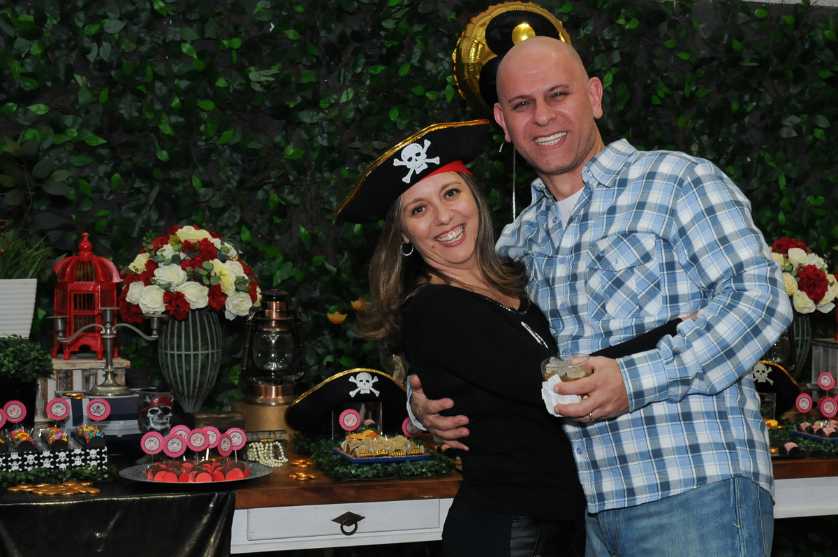 foto dos pais da giulia felizes em frente a mesa piratas do caribe no Buffet Espaço Vila da Arte