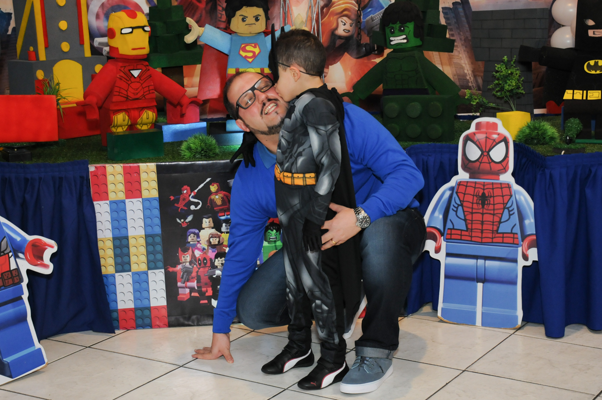 matheus dando beijinho no papai em frente a mesa decorada lego no buffet fábrica da alegria, osasco