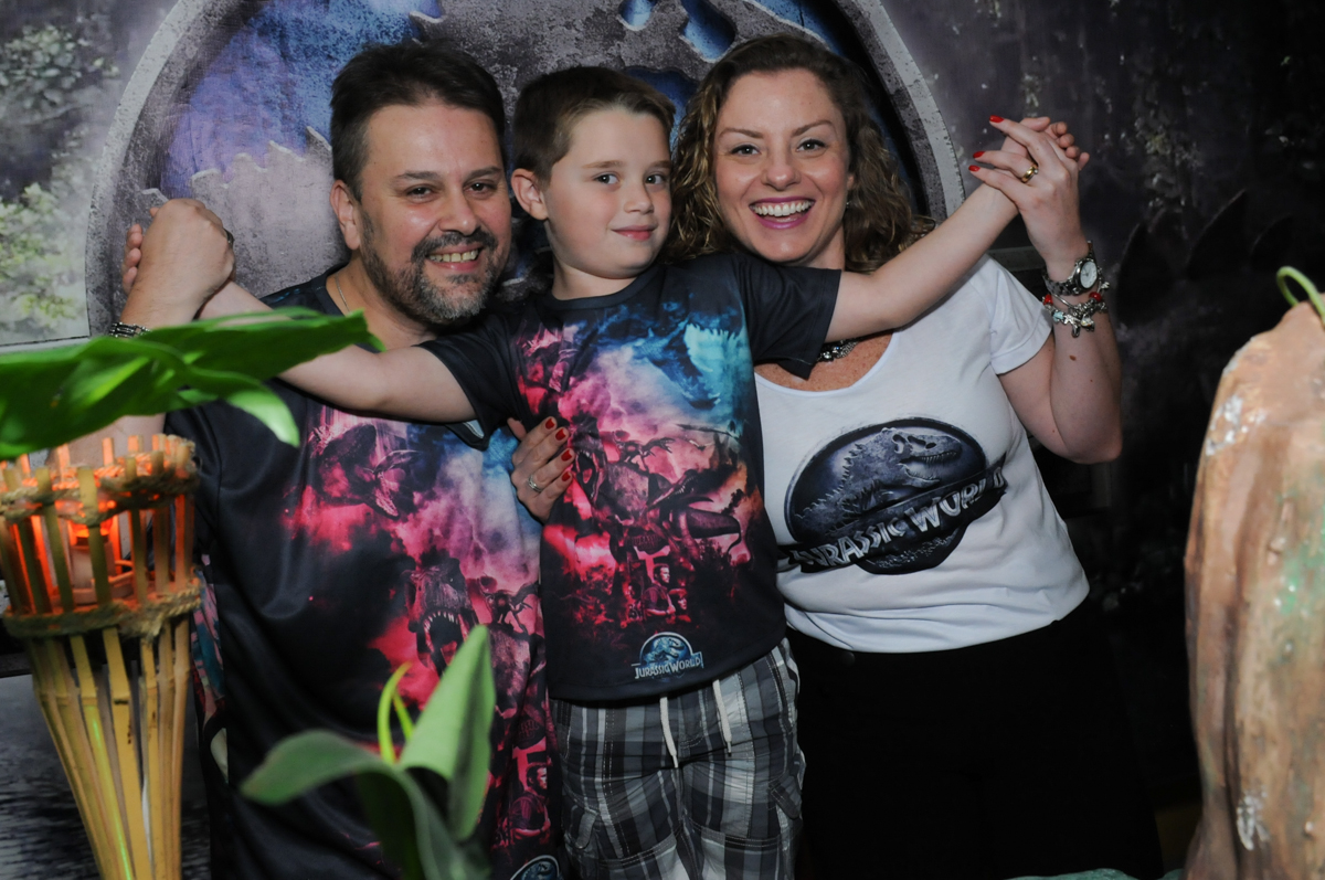 thiago abraçando o papai e a mamãe em frente a mesa decorada dos dinossauros no buffet espaço boo, Lapa, São Paulo
