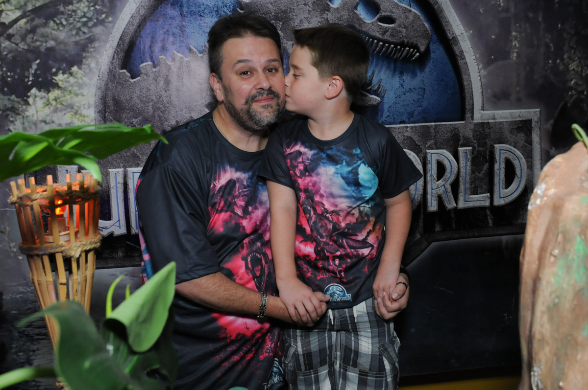 papai ganhando beijinho de thiago em frente a mesa decorada dos dinossauros no buffet espaço boo, Lapa, São Paulo