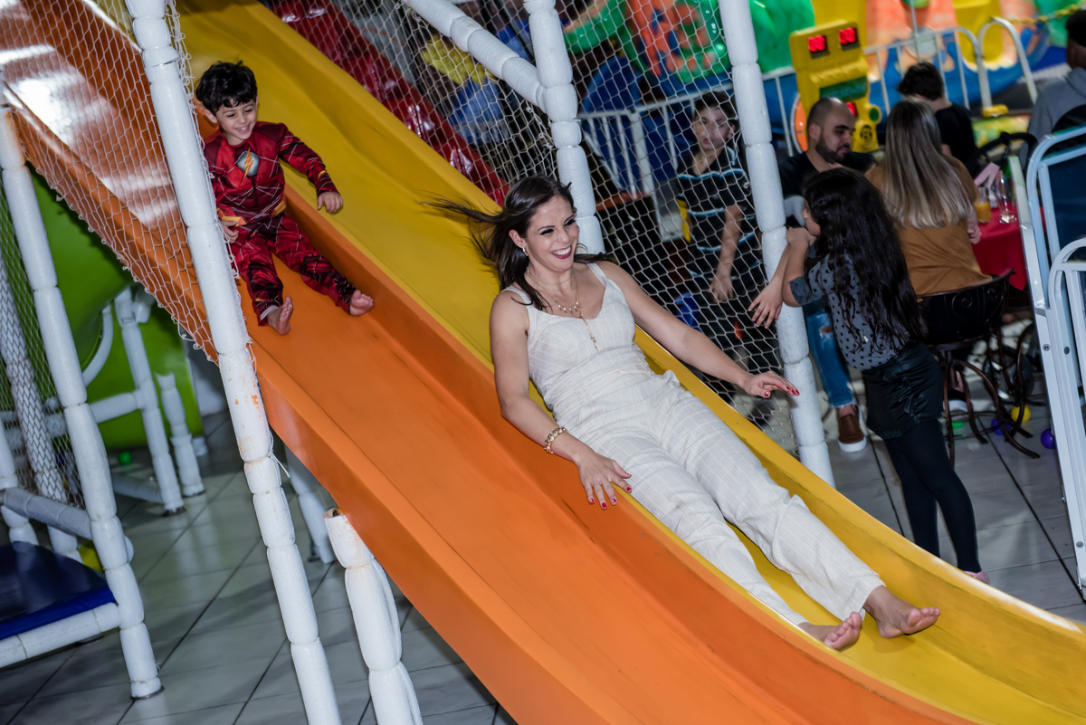 a mãe do aniversariante brinca no tobogã