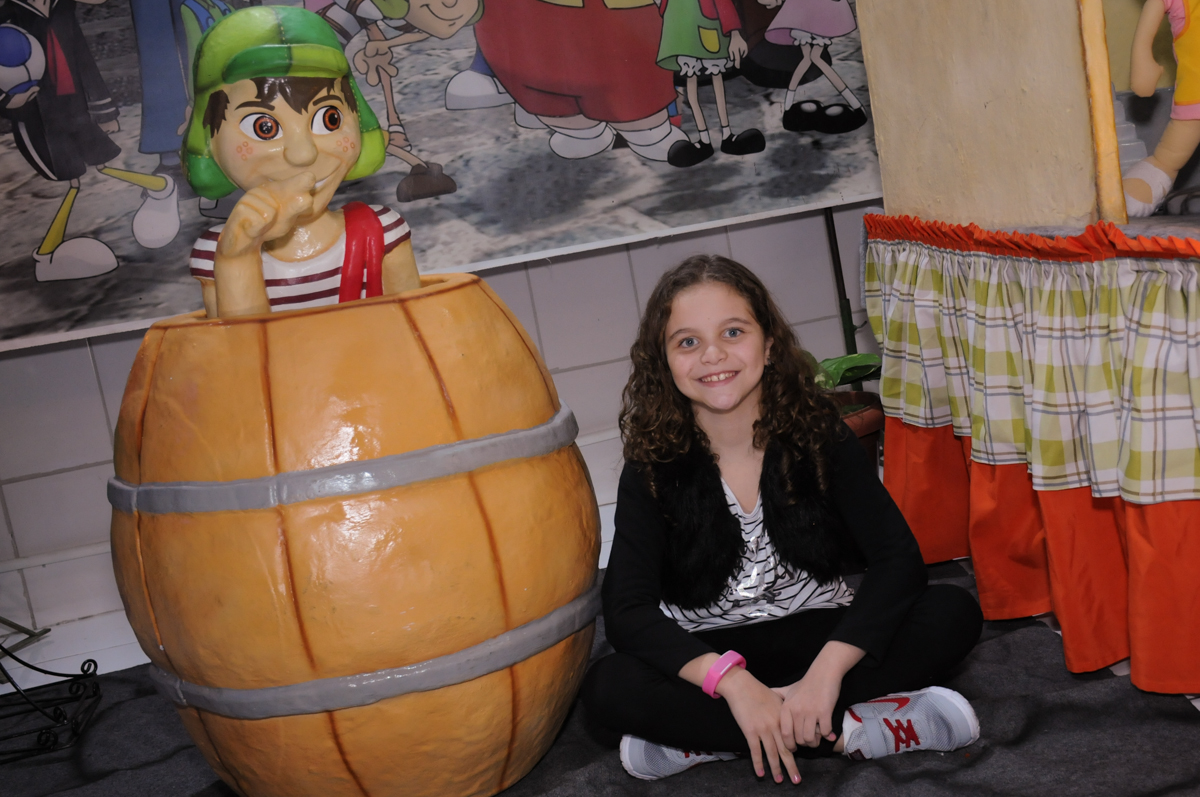 sentada em frente a mesa decorada chaves no Buffet Espaço Parabéns, Lapa