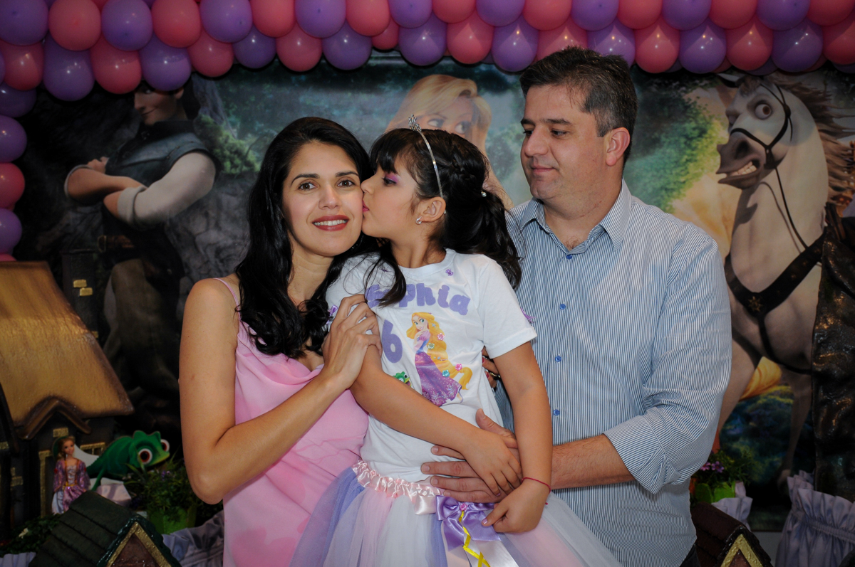 beijinho da aniversariante em sua mãe em frente a mesa tema rapunzel no Buffet Fábrica da Alegria Osasco, São Paulo