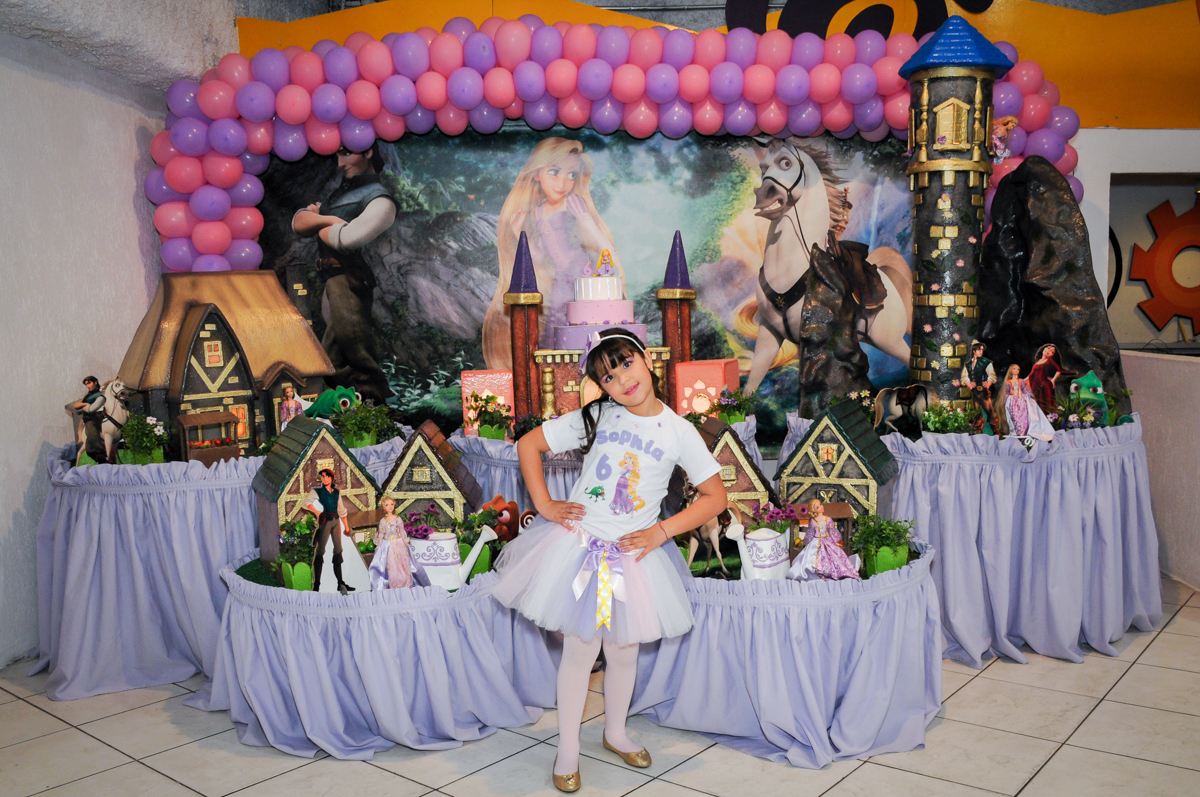 aniversariante posa para foto em frente a mesa tema rapunzel no Buffet Fábrica da Alegria Osasco, São Paulo